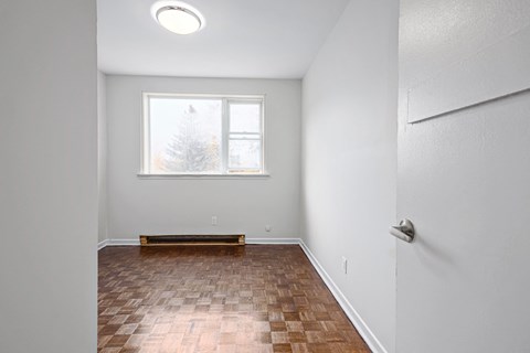 an empty living room with wood flooring and a window