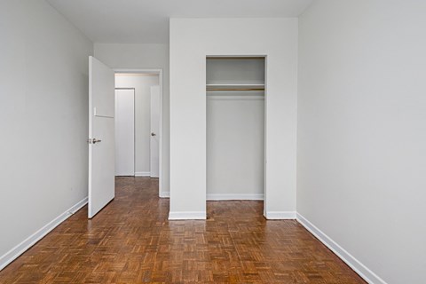 an empty room with white walls and wooden floors and closet doors