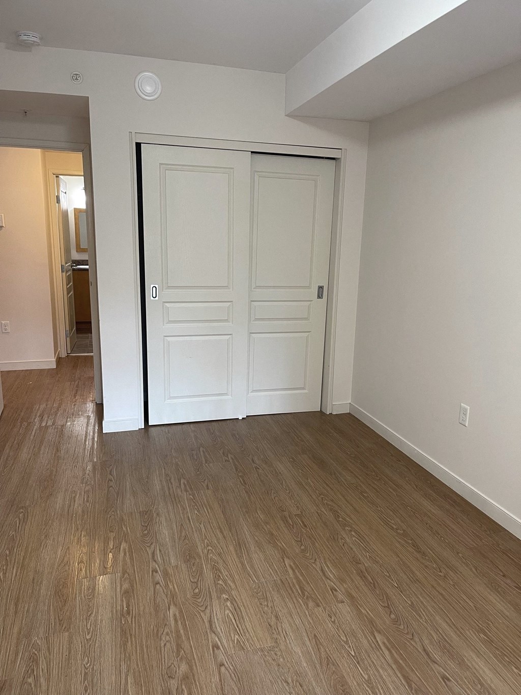 an empty living room with white walls and wooden floors