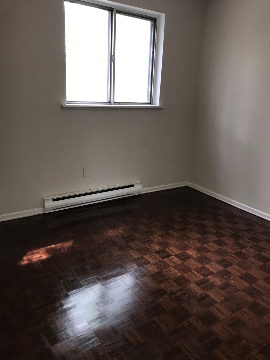 an empty room with wooden floors and a window