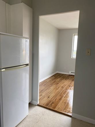 an empty kitchen with a refrigerator and a wooden floor