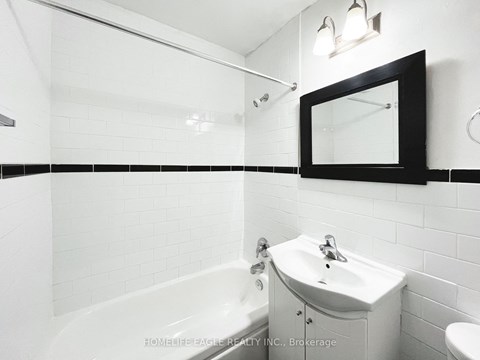 a white bathroom with a sink and a tub and a mirror