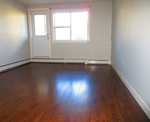 an empty living room with wooden floors and a window