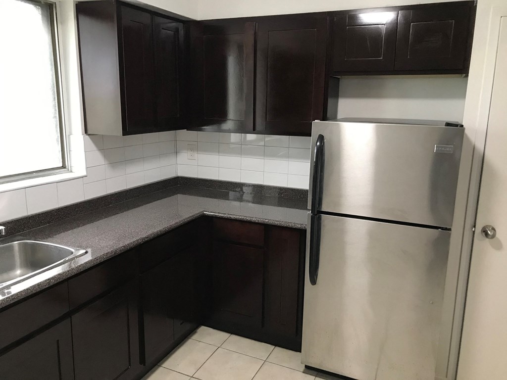a kitchen with black cabinets and a stainless steel refrigerator