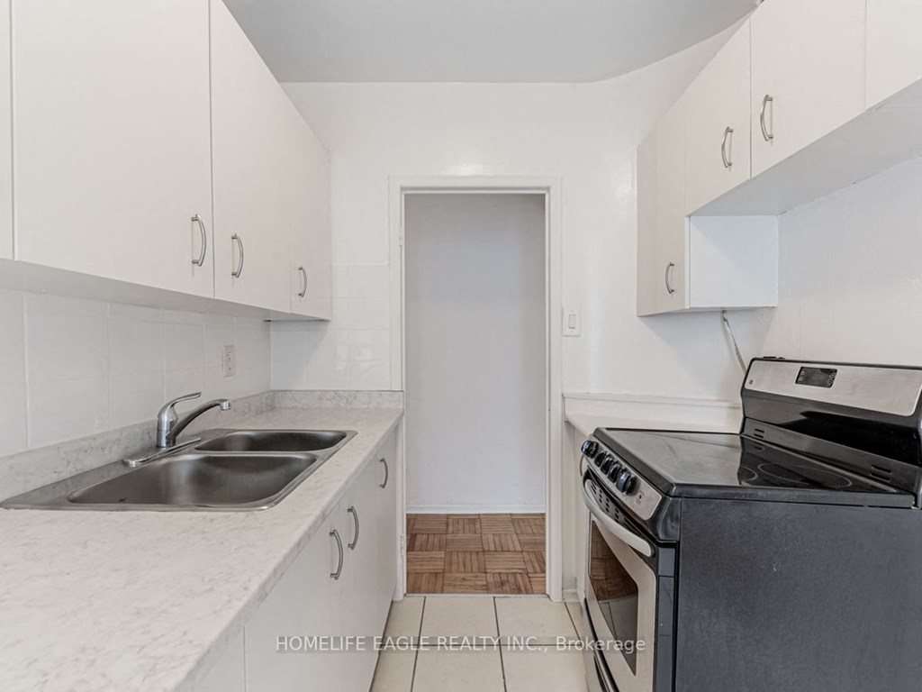 a kitchen with white cabinets and a black stove and sink