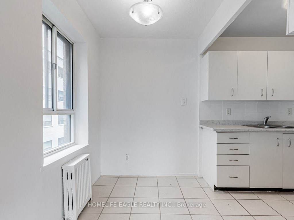 an empty kitchen with white cabinets and a window