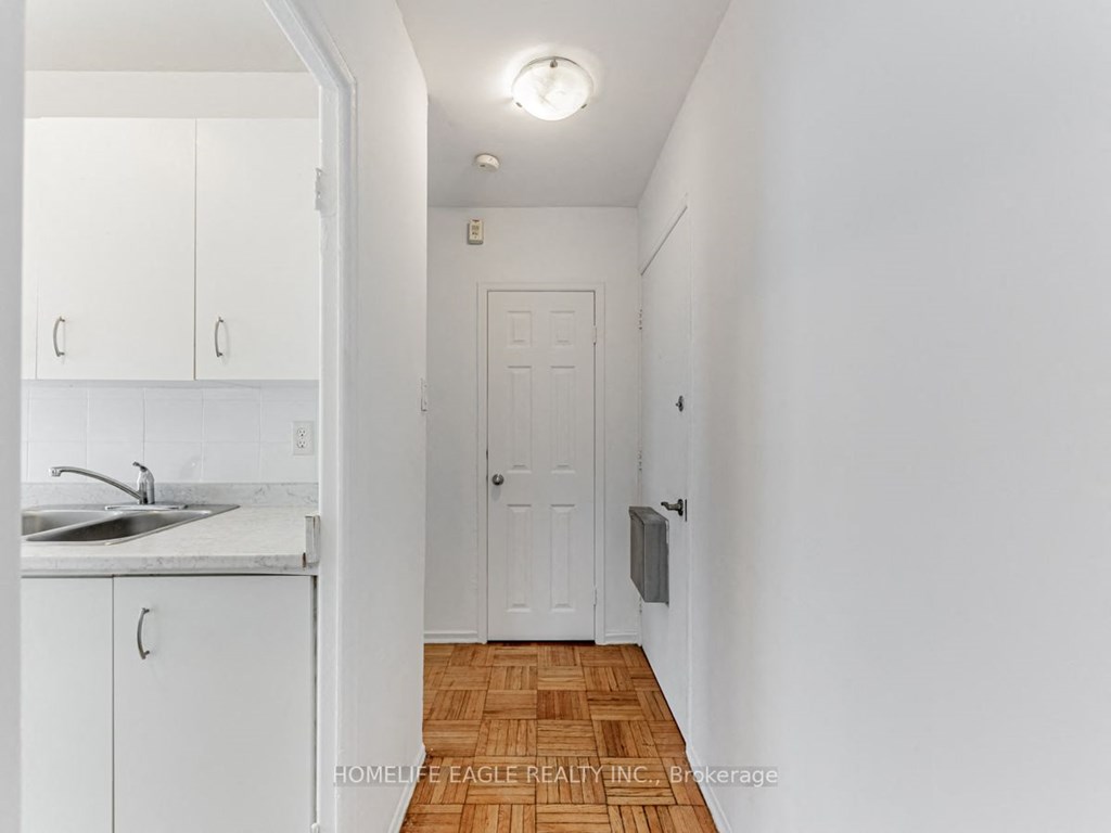 a small kitchen with white cabinets and a white door