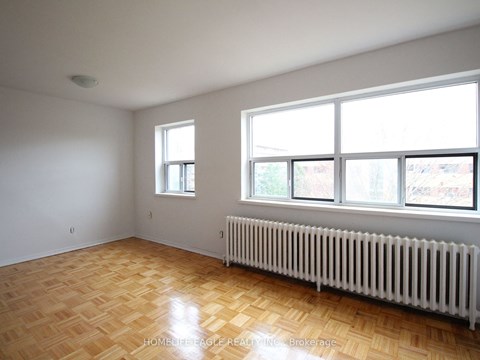 the living room of a house with a wood floor and a radiator and large windows