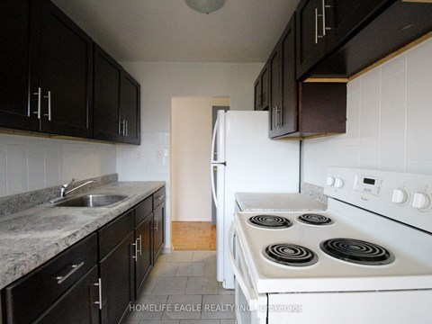 an empty kitchen with white appliances and black cabinets