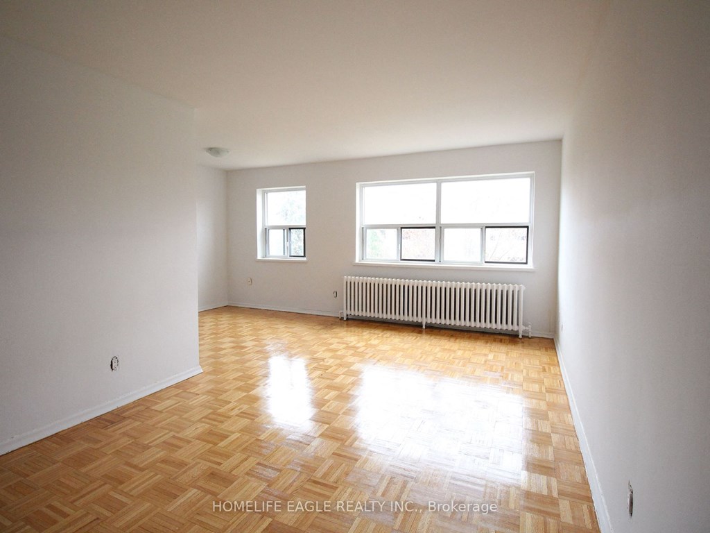 an empty living room with a wood floor and a radiator
