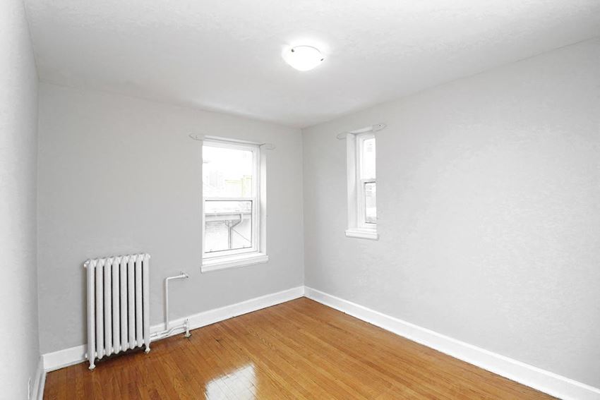 an empty room with a radiator and two windows