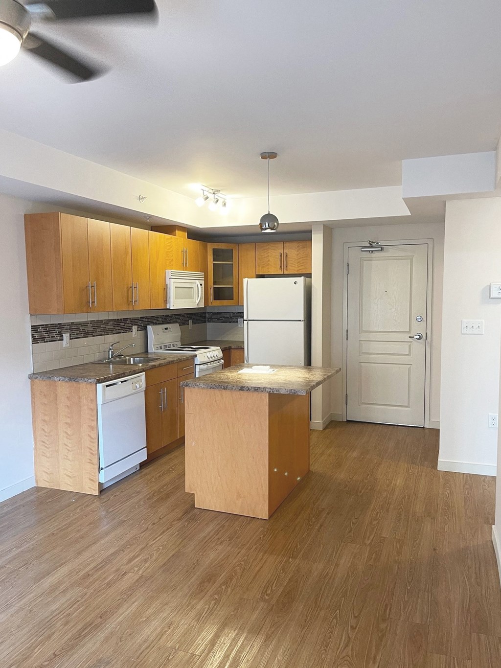 an empty kitchen with wooden cabinets and a white refrigerator