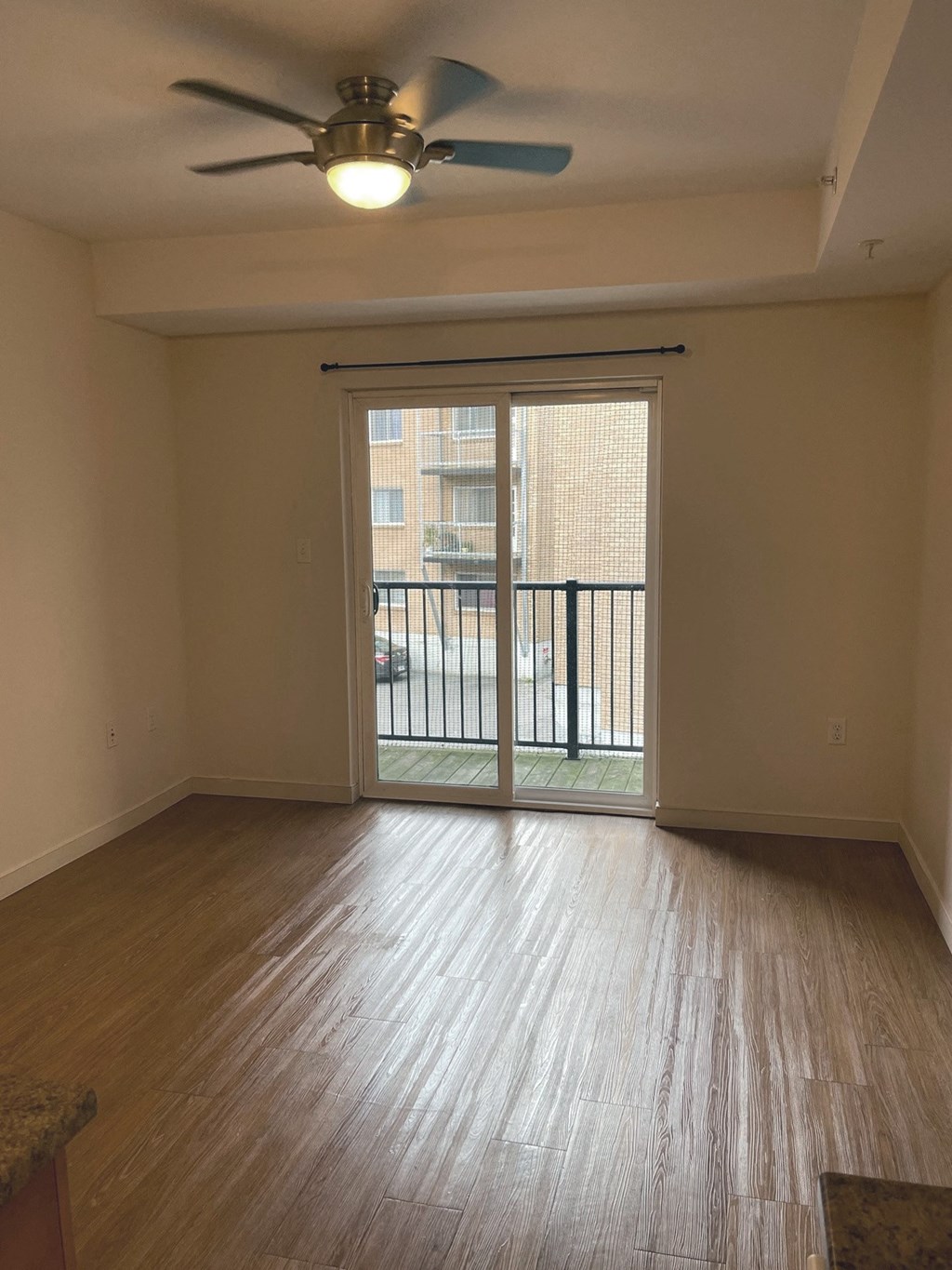 an empty living room with a ceiling fan and a balcony