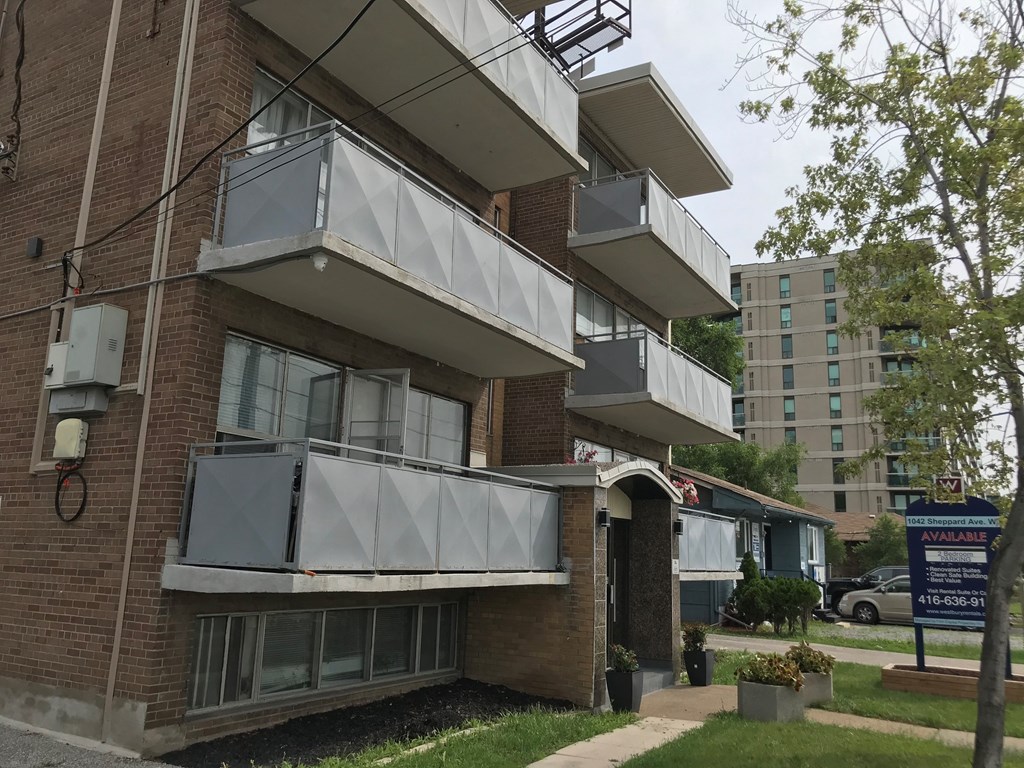 a brick apartment building with three balconies and a sidewalk