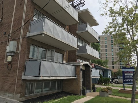 a brick apartment building with three balconies and a sidewalk