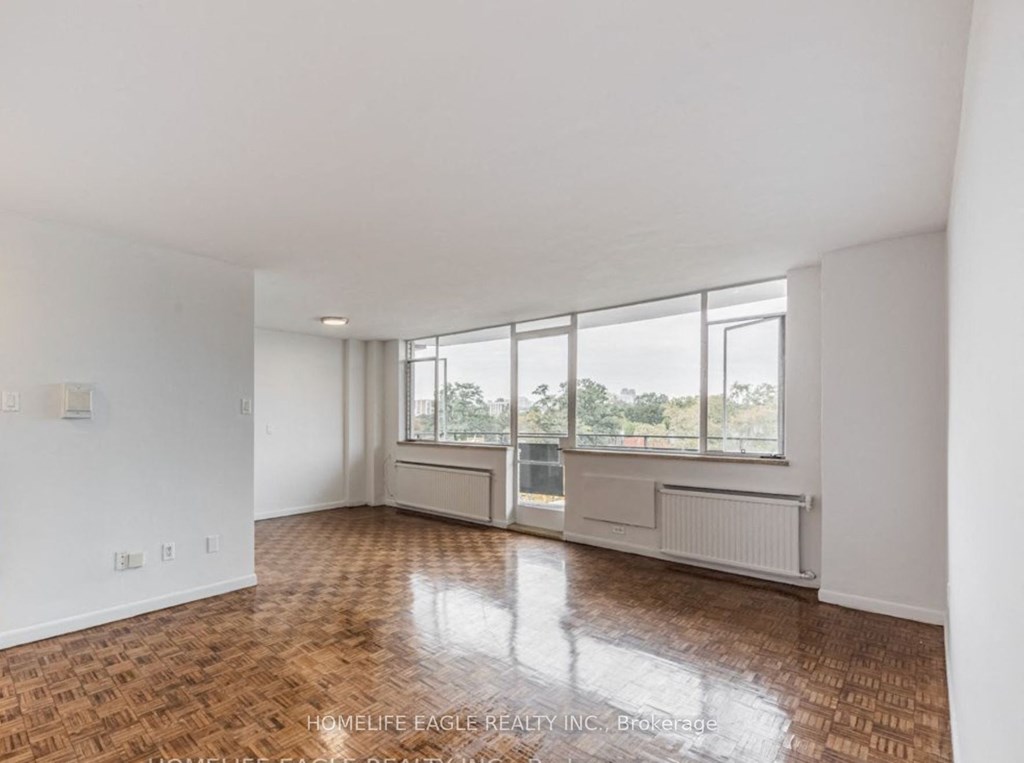 an empty living room with large windows and wooden floors