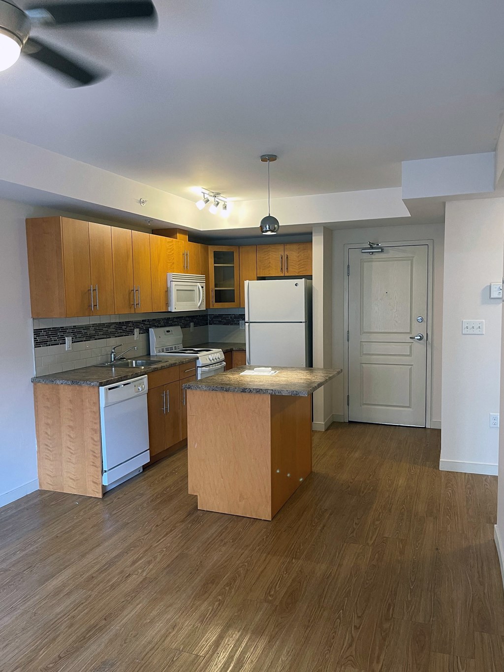 an empty kitchen with wooden cabinets and a refrigerator