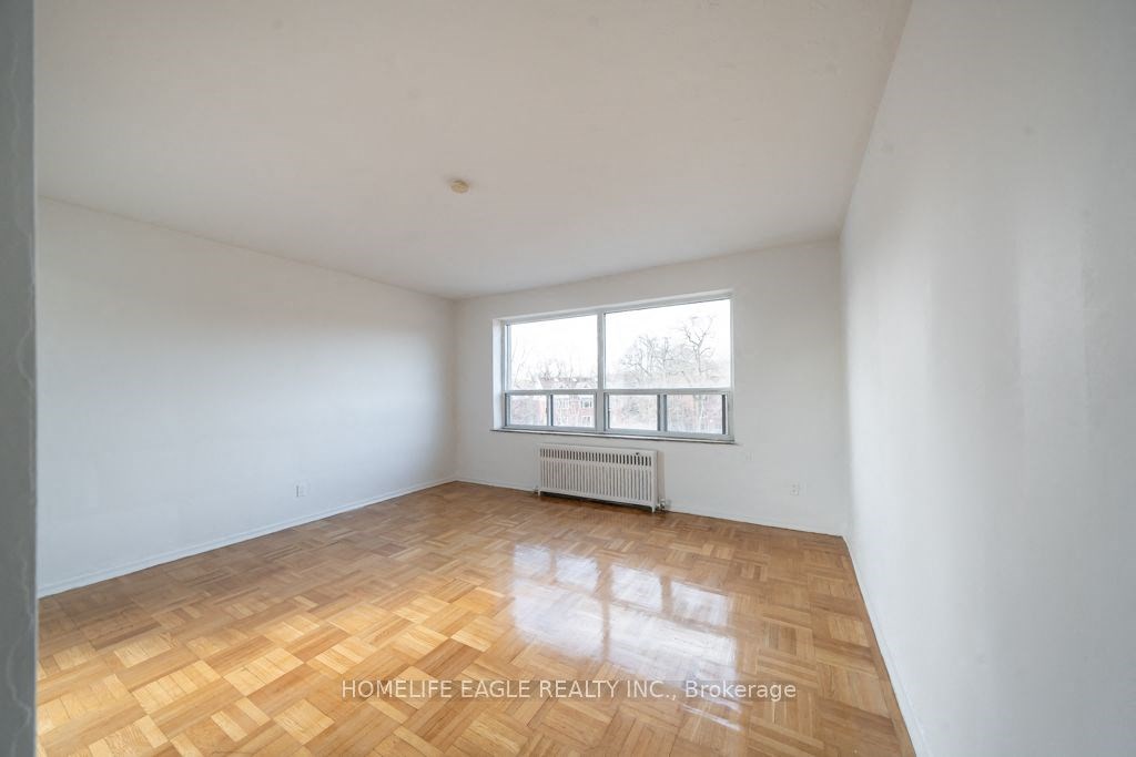 an empty living room with a window and wooden floors