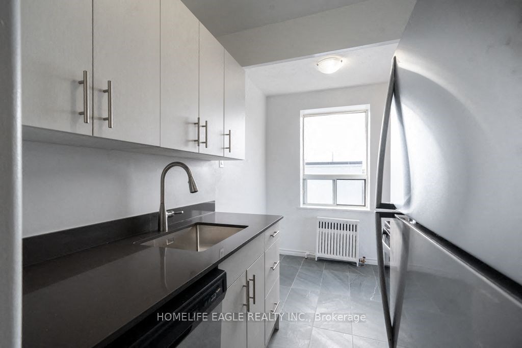 a white kitchen with stainless steel appliances and a window