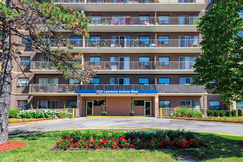 an apartment building with a lawn and flowers in front of it