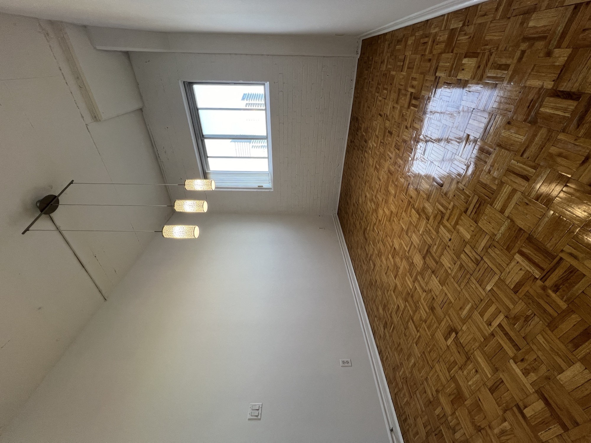 an empty room with a window and a wooden wall