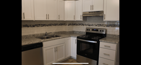 a kitchen with white cabinets and black and white appliances