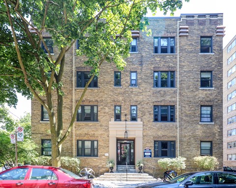 the exterior of a brick building with a tree in front of it