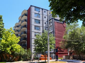 an apartment building with a red and gray facade and trees