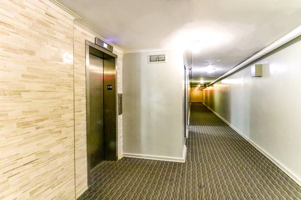 an empty hallway with a stainless steel elevator door