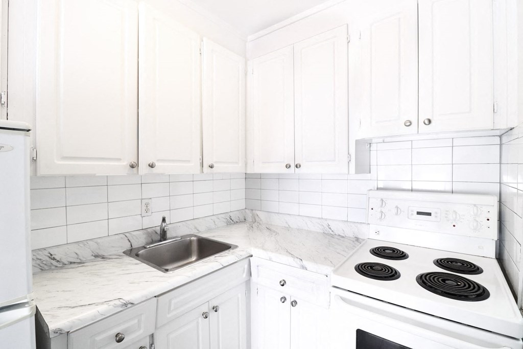 a white kitchen with marble counter tops and white cabinets