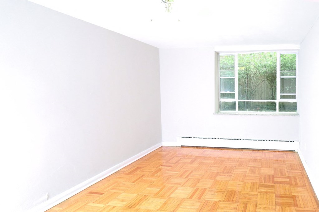 an empty room with a window and wooden floors
