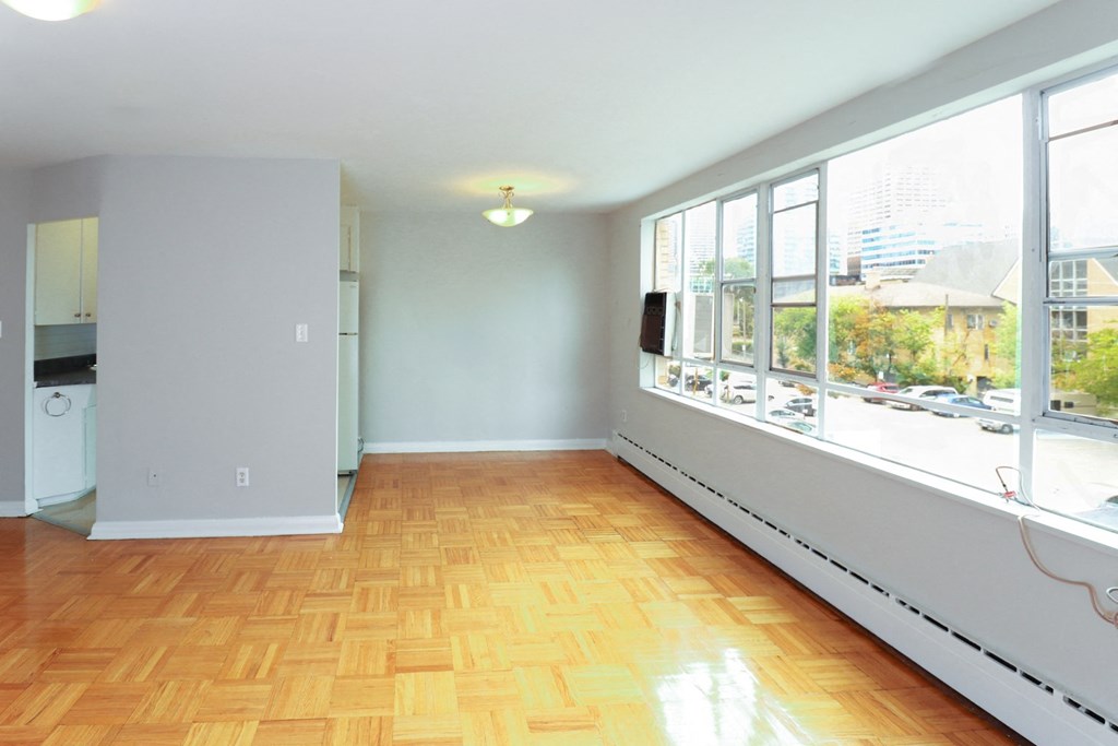 an empty living room with a large window and wooden floors
