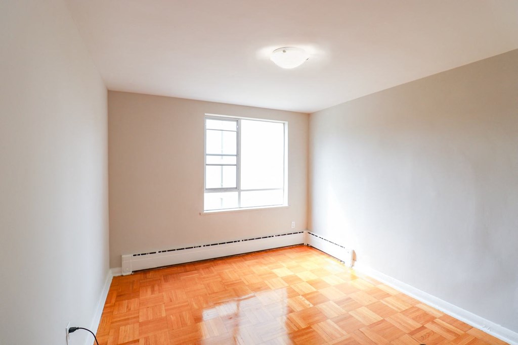 an empty room with a window and wooden floors