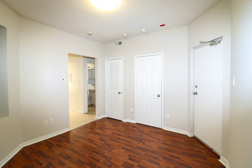 an empty living room with wood floors and white walls