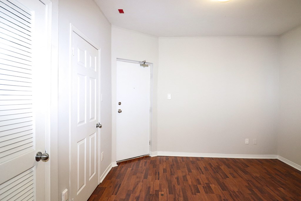a bedroom with white walls and wood floors and a white door