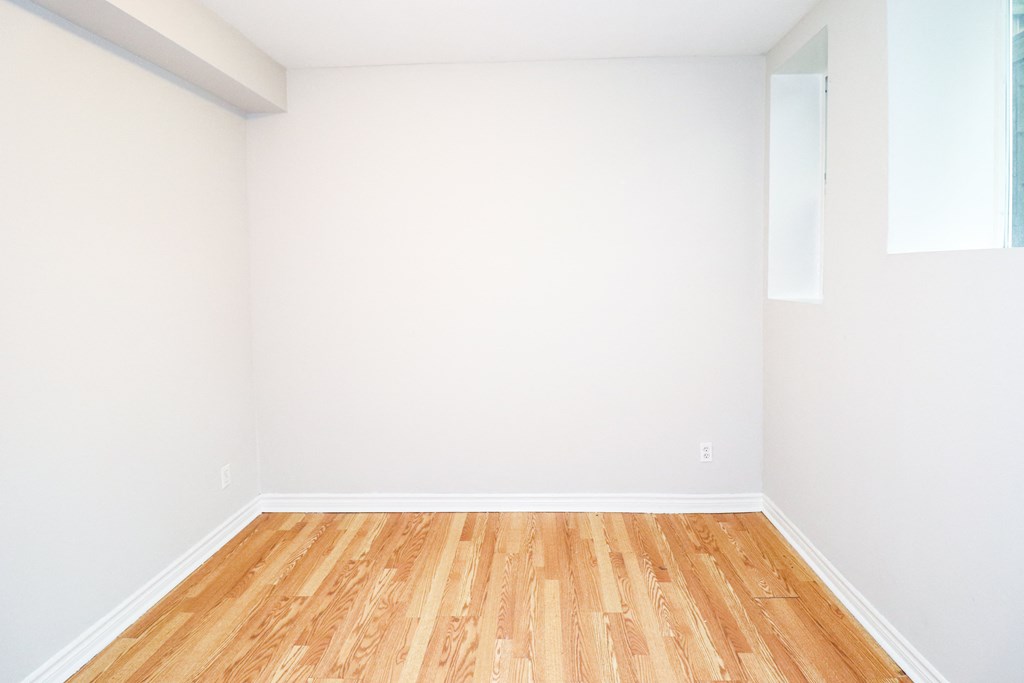 an empty room with wooden floors and white walls
