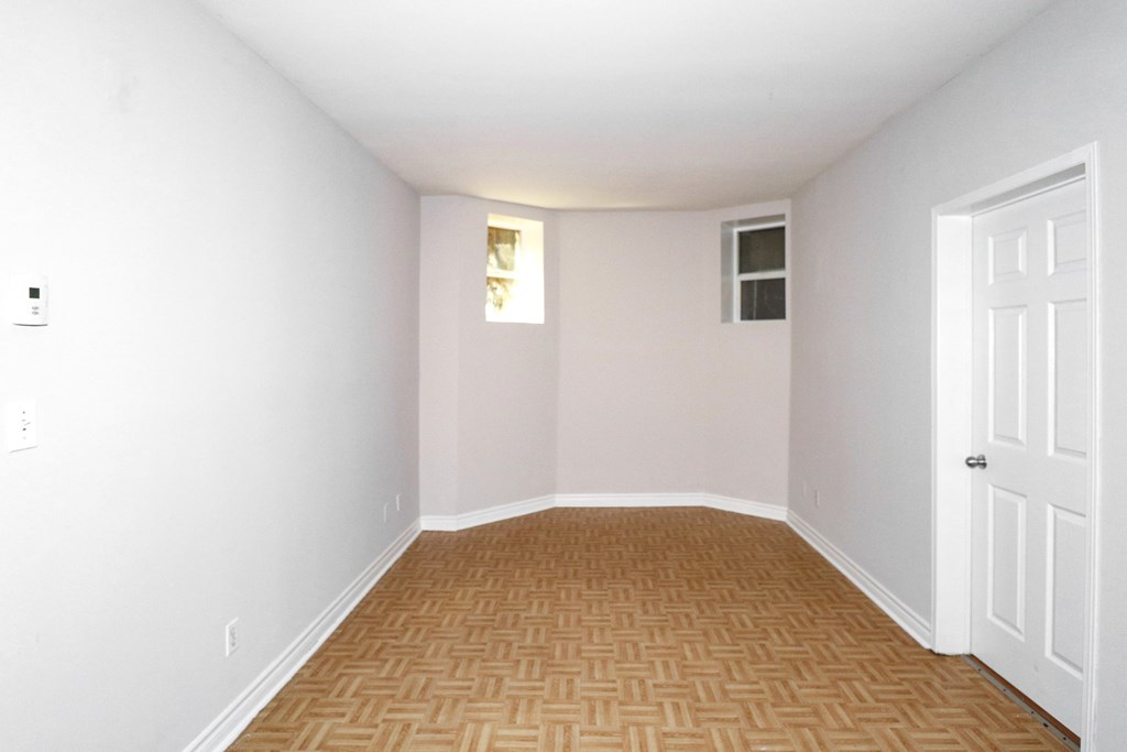 an empty room with white walls and a wooden floor and a white door