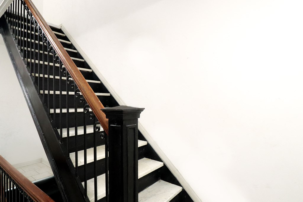 a stairwell with black and white stairs and a black railing and white walls
