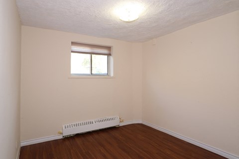 a small room with a wooden floor and a window and a radiator