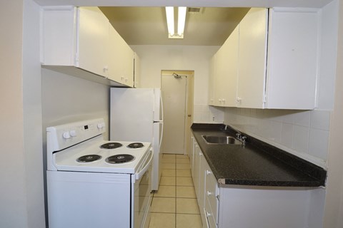 a kitchen with white appliances and black counter tops and white cabinets