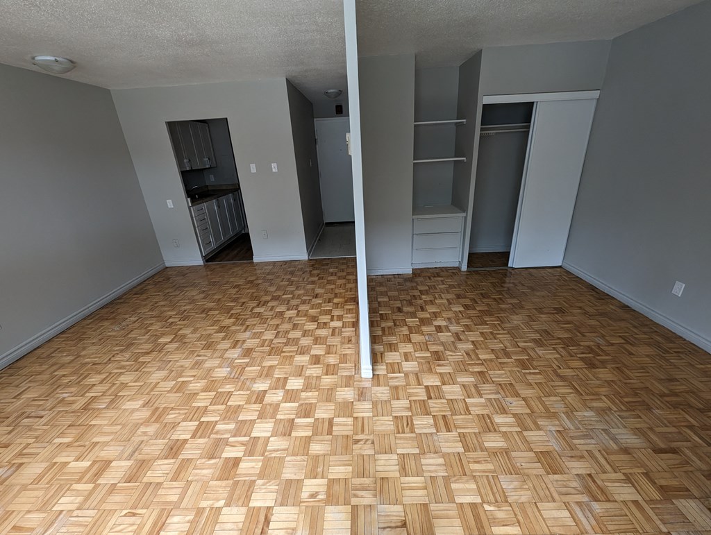 an empty living room with wood flooring and a closet