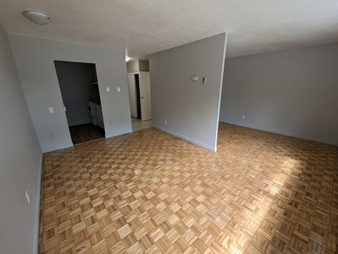 an empty living room with wood flooring and grey walls