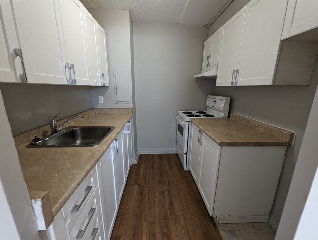 an empty kitchen with white cabinets and a sink