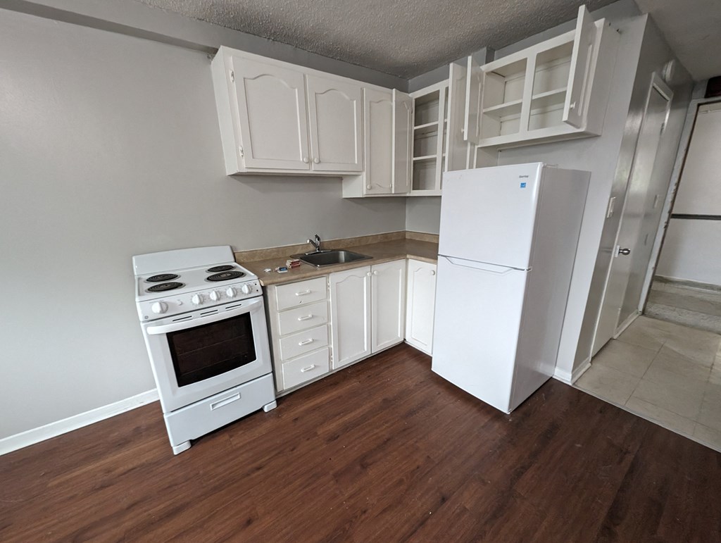 an empty kitchen with white appliances and a refrigerator