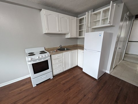 an empty kitchen with white appliances and a refrigerator
