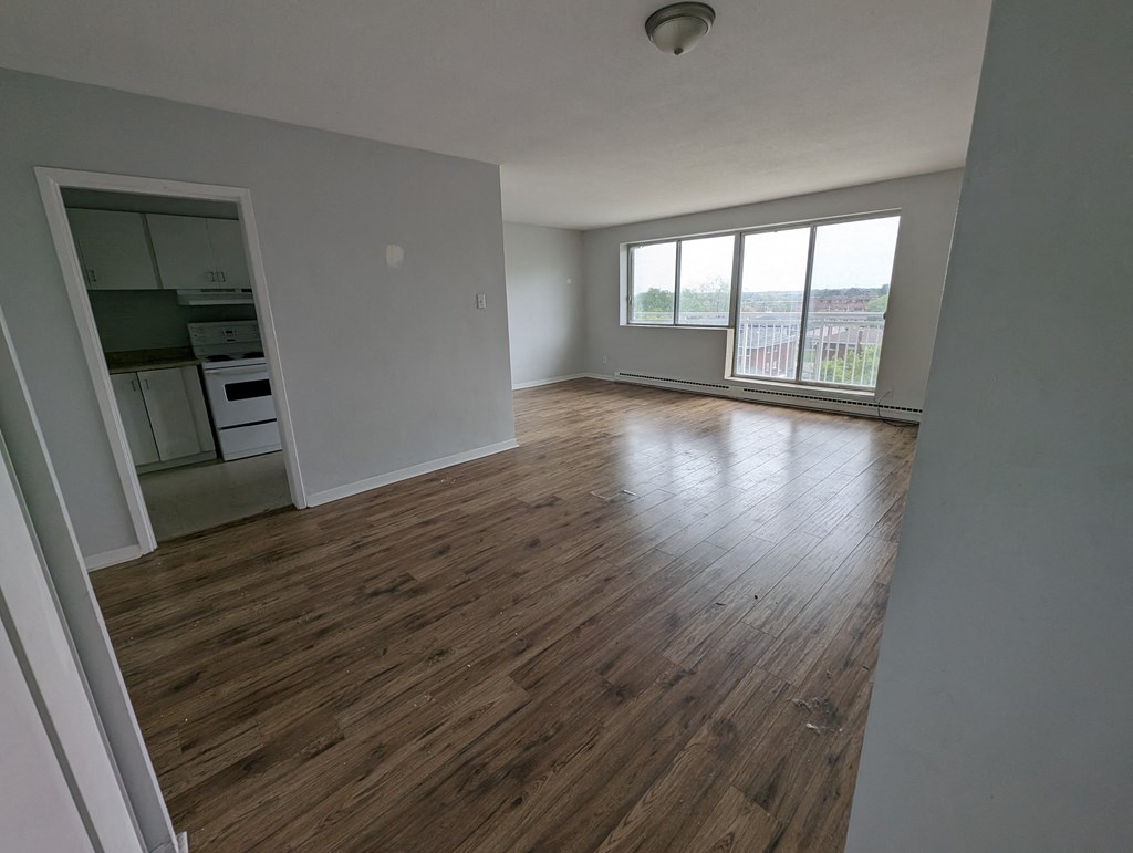 an empty living room with wood flooring and a window