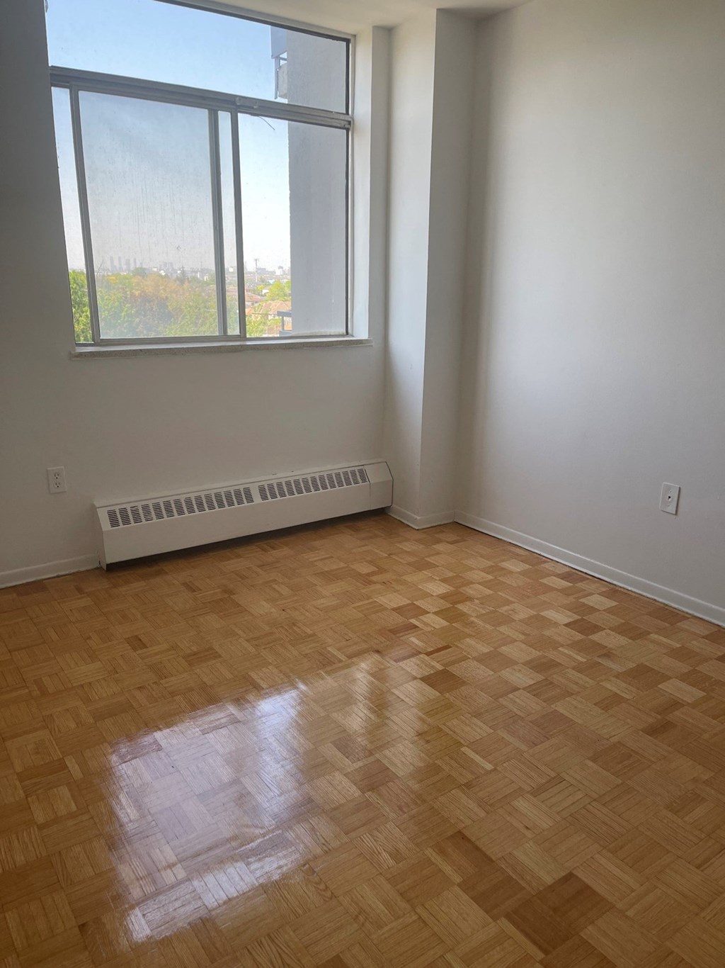 an empty room with a wooden floor and a large window