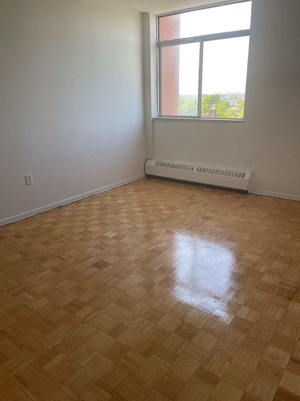 an empty room with a window and a radiator