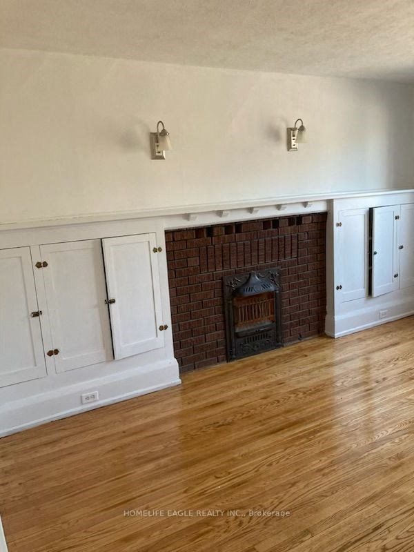 a living room with a brick fireplace and white cabinets