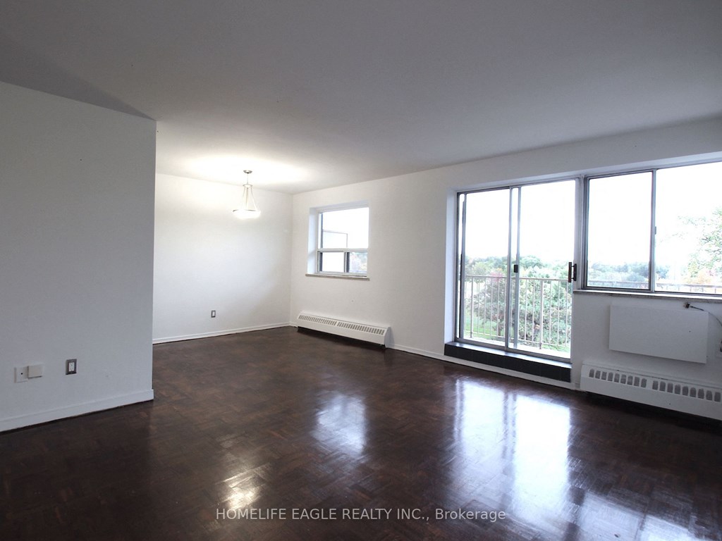 an empty living room with wood floors and a large window
